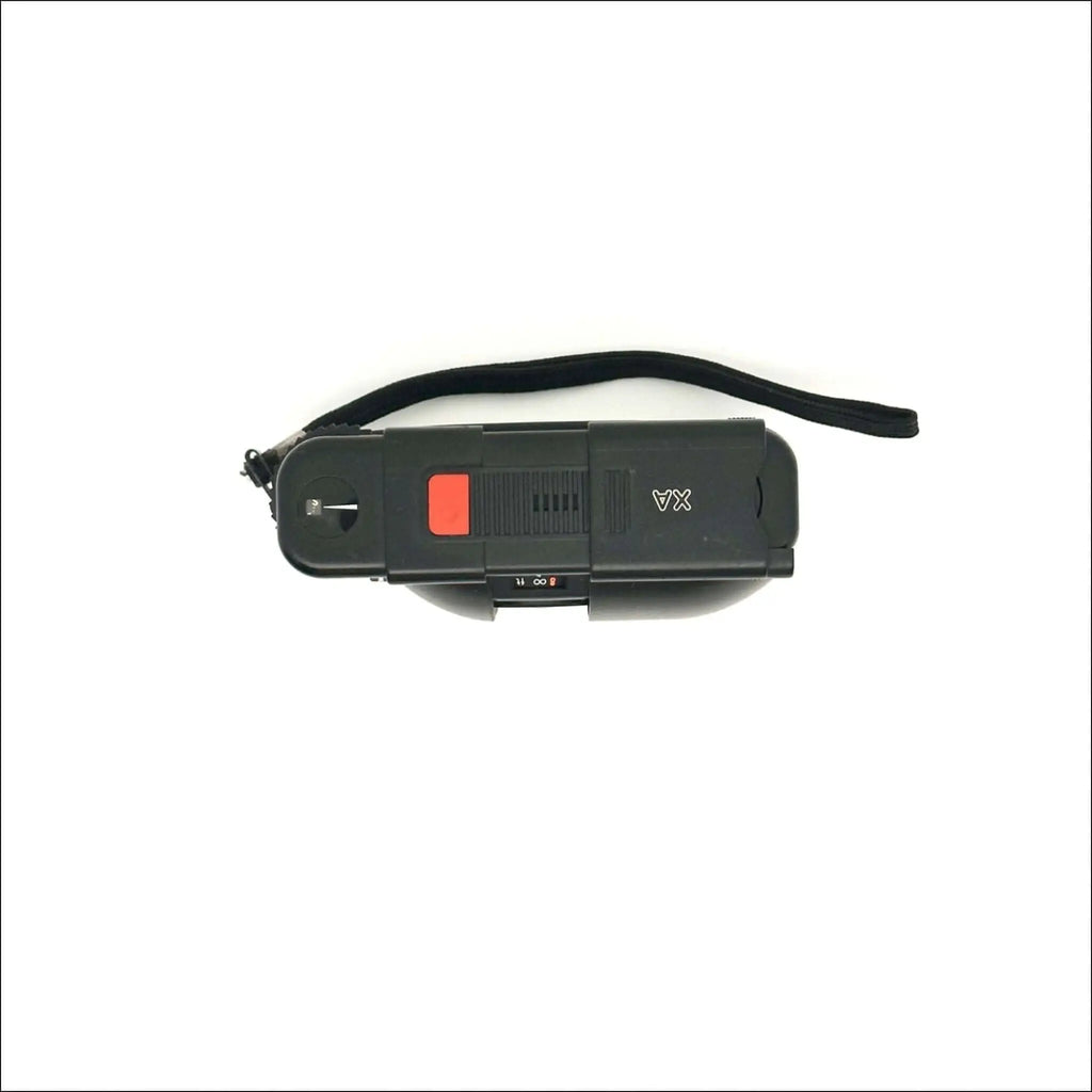 Black plastic handheld device with a red button and black wrist strap.