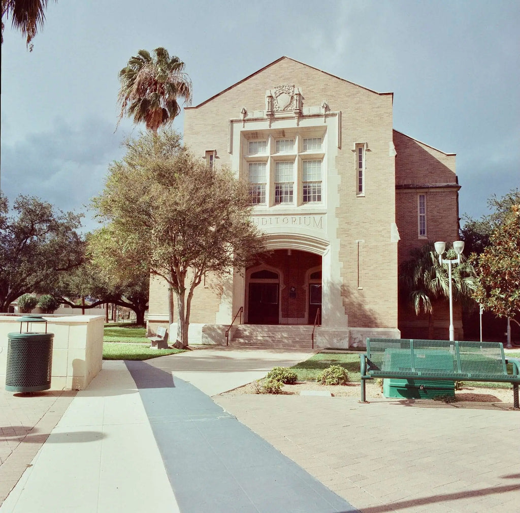 Beige brick building with arched entrance and white stone trim, featuring the word ’editioum’ above it.