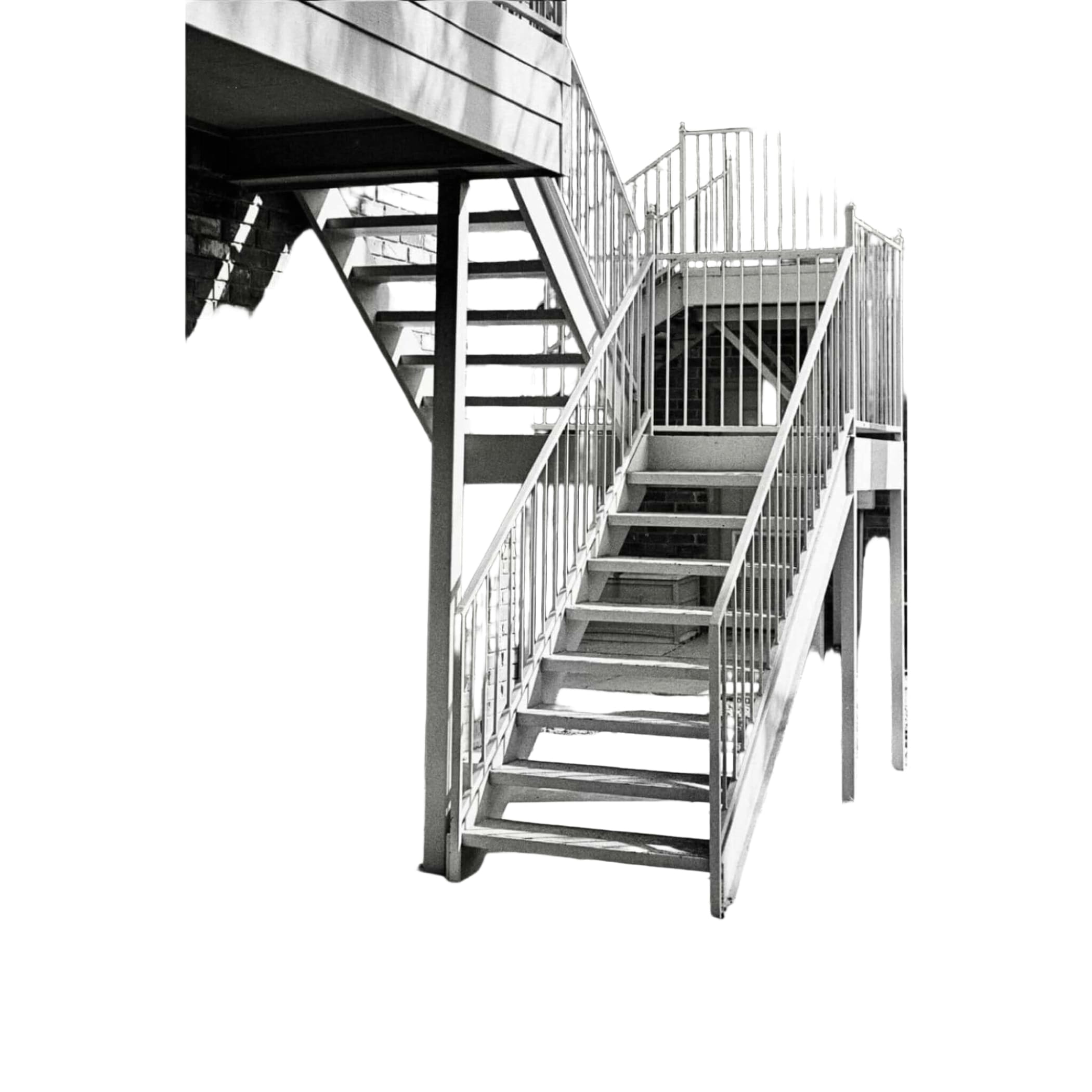 Metallic staircase with vertical railings and concrete steps against a brick wall