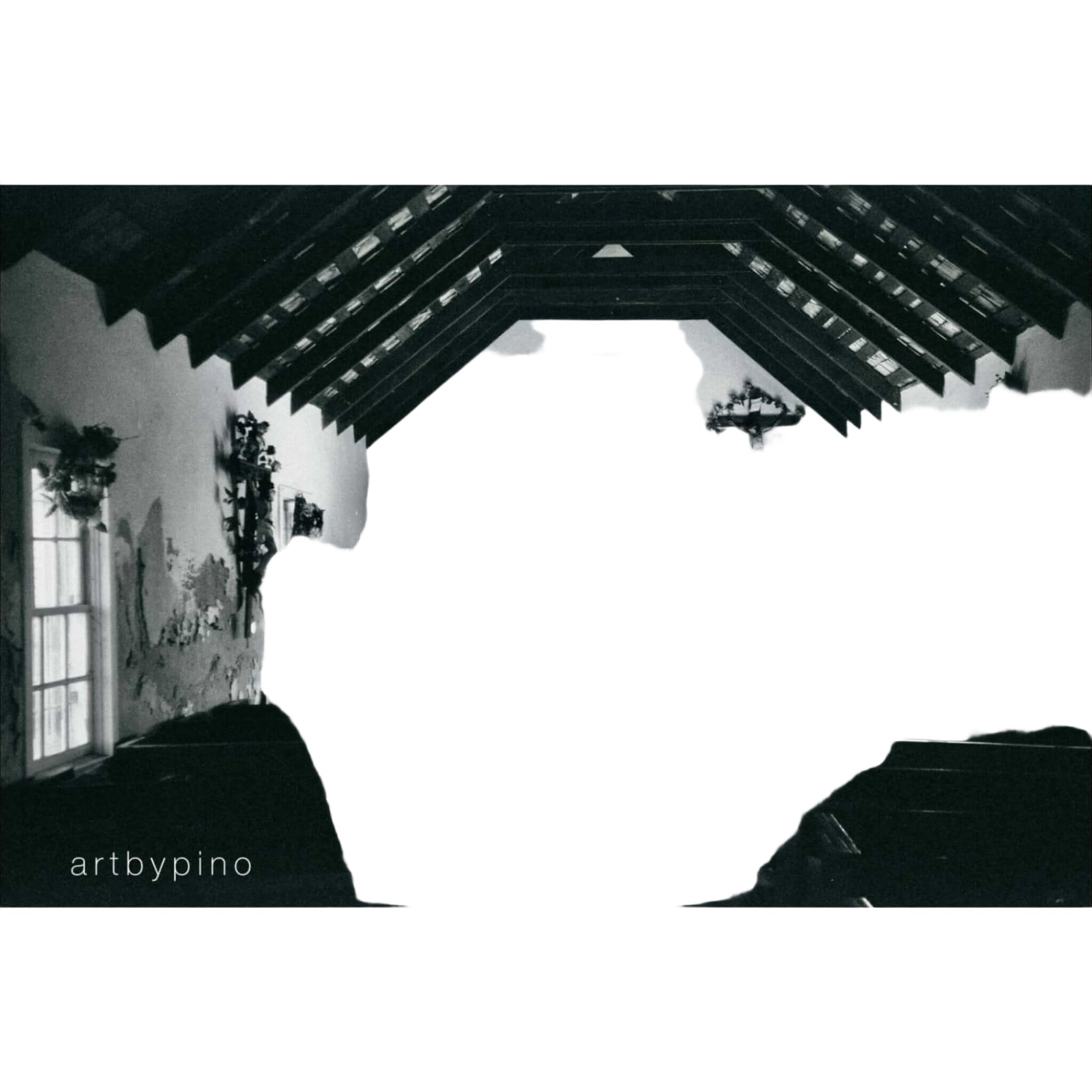 A black-and-white photograph of a rustic church interior with exposed wooden beams, floral arrangements on the altar, and pews lining the nave.