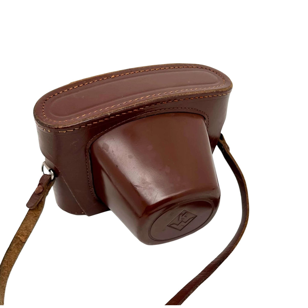 Brown leather camera case with stitched edges and a matching strap.