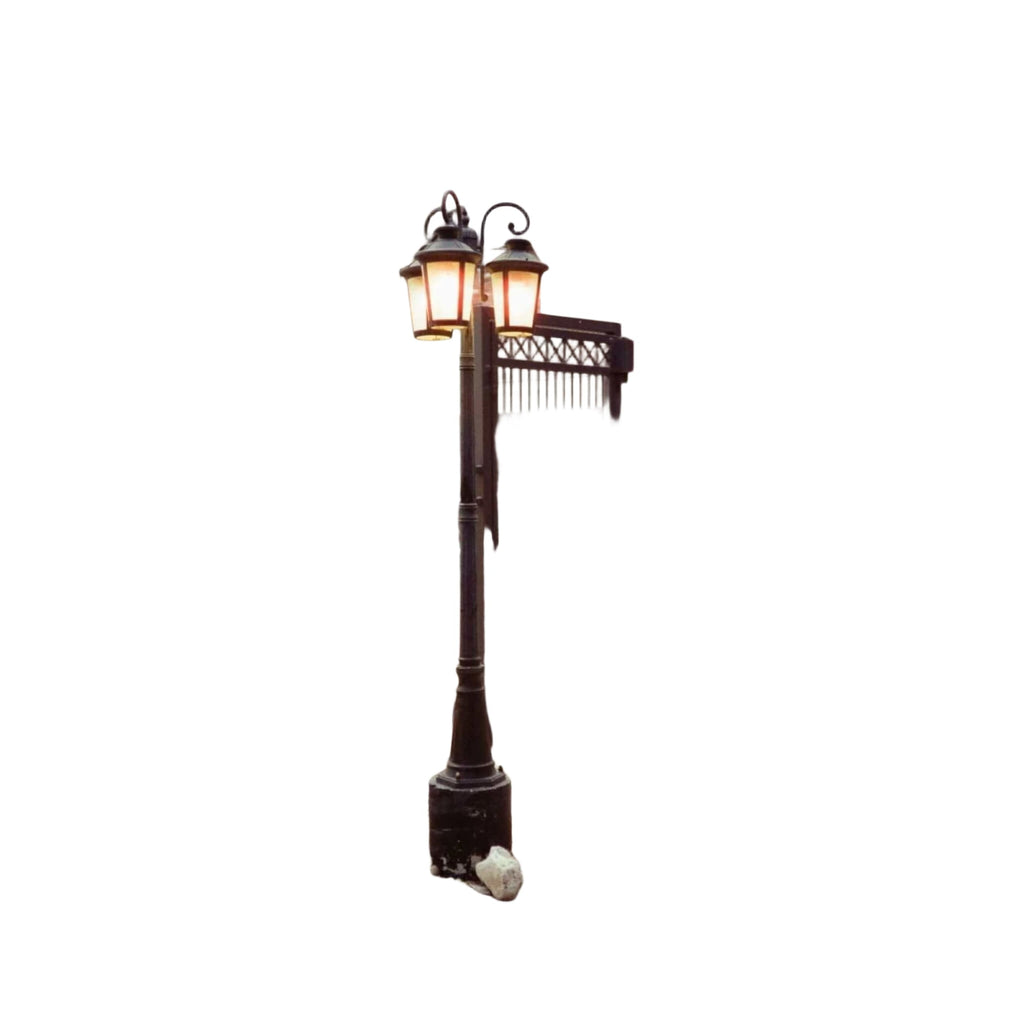 Black wrought iron lamppost with two glowing lanterns.