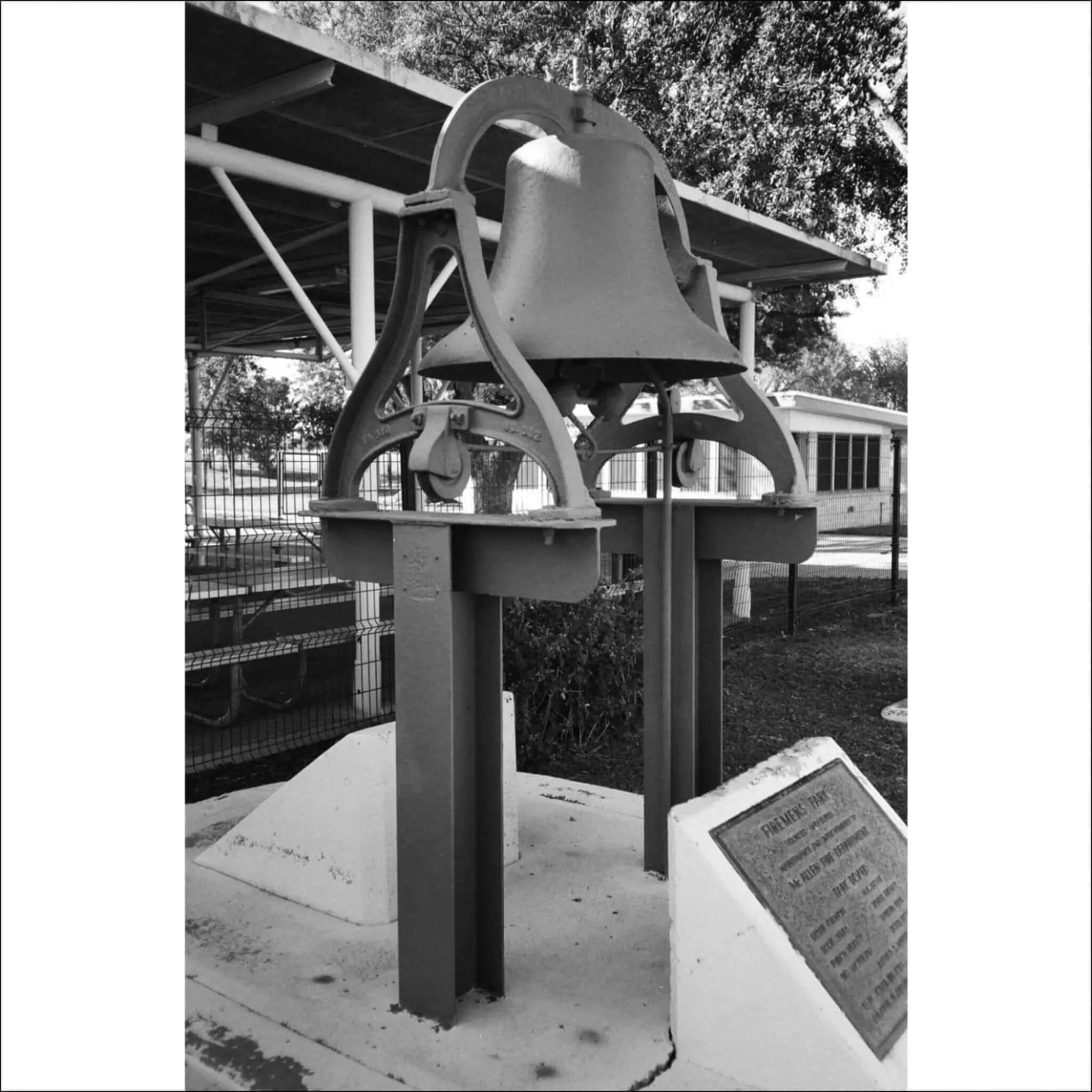 Black and white photo of a historic bell monument with an information plaque.
