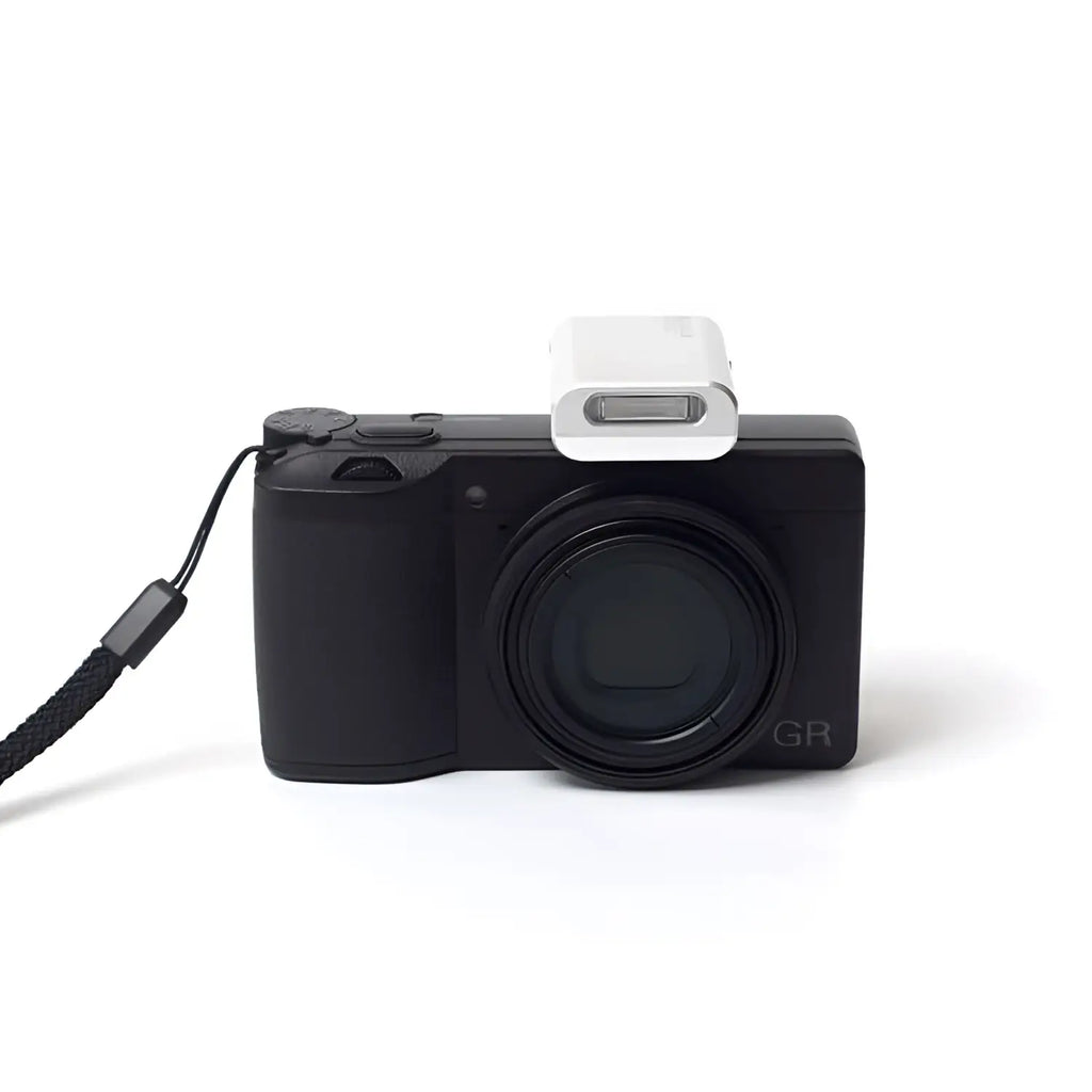 Black compact camera with a white flash attachment and black wrist strap.