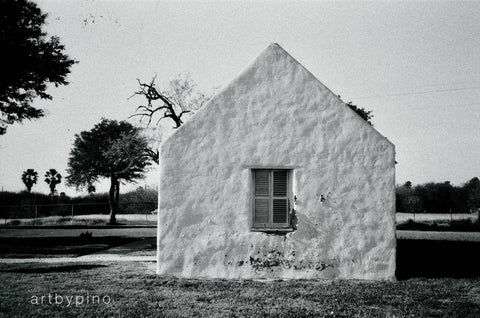 Weathered white stucco house in cinematographic black and white photography.