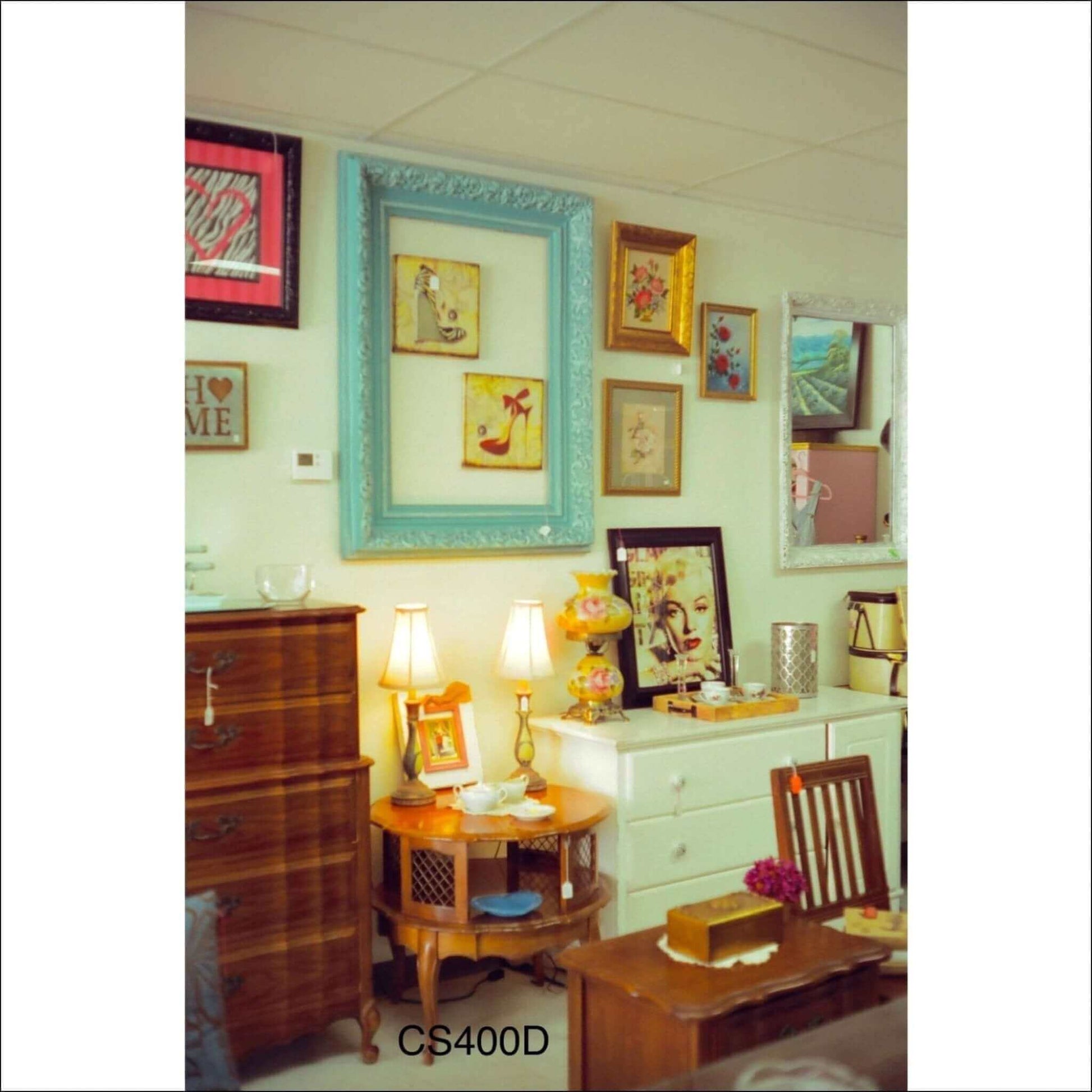 Cozy vintage decor featuring framed art, a lamp, and wooden furniture captured with Cinestill 400D film.