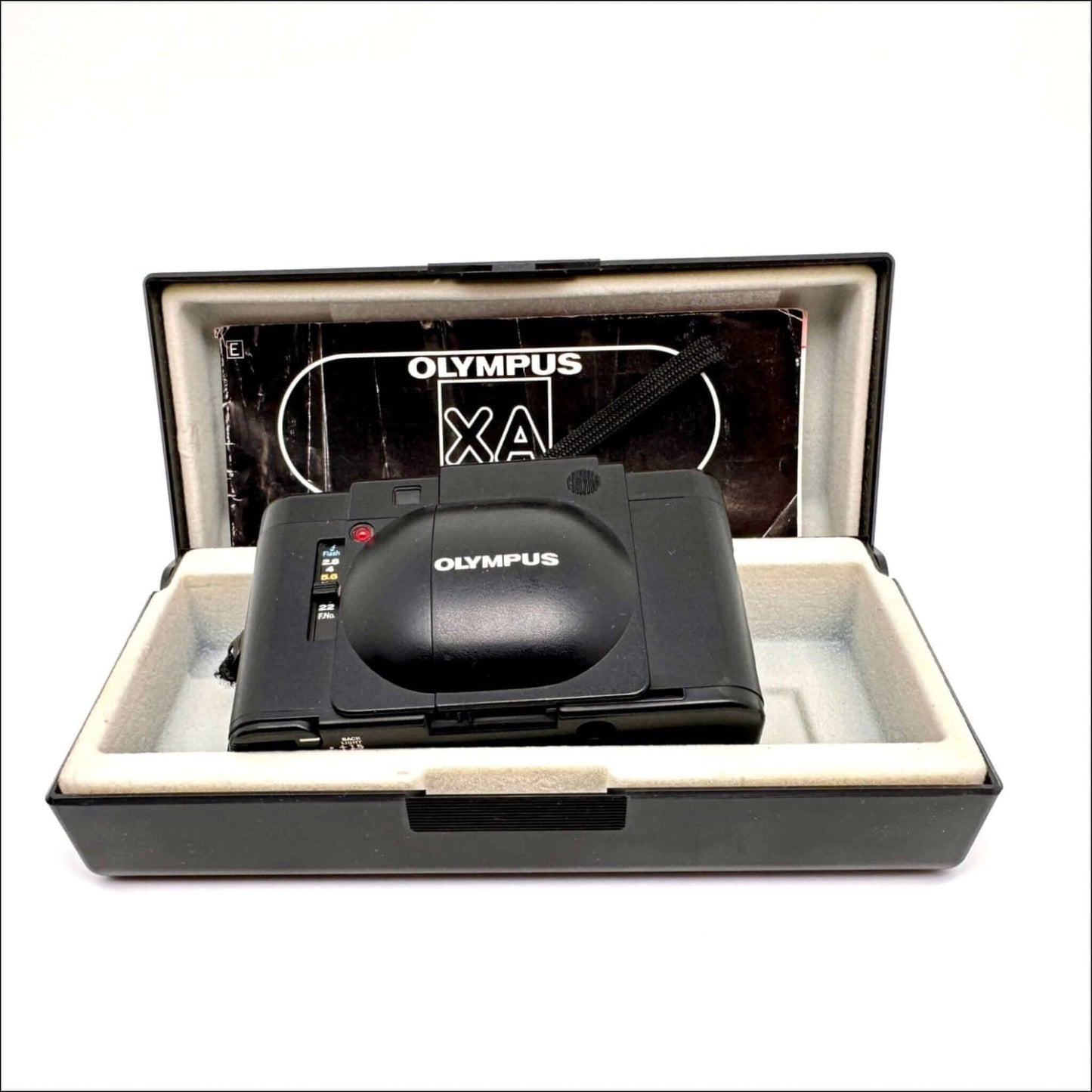 Olympus XA vintage 35mm film camera in original case with instruction manual, showcasing cosmetic quality and features.